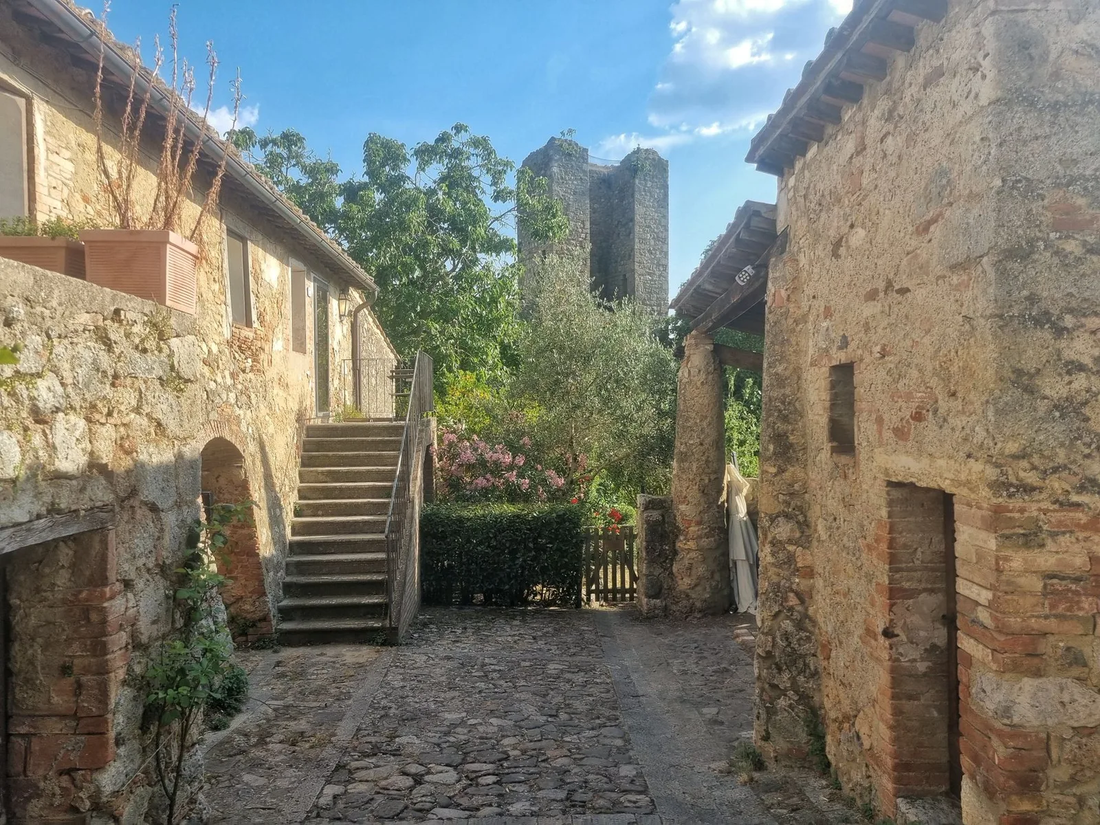 Zonnig stenen straatje met Toscaanse huizen en een middeleeuwse toren in Monteriggioni